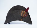 an old hat with a feather on top of it on a white surface
