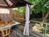 a wooden deck with a table and chairs under a canopy