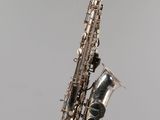 a close up of a saxophone hanging from a string on a wall