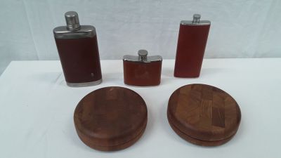 three flasks and a wooden coaster on a table