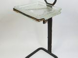 une image représentant un plateau en verre muni d'une poignée, posé sur un support métallique