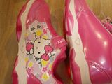 pair of pink hello kitty shoes sitting on top of a wooden floor