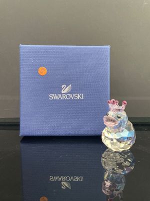 une petite figurine en verre posée sur une table, à côté d'une boîte bleue