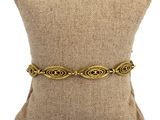 un bracelet plaqué or posé sur un coussin, sur un fond blanc