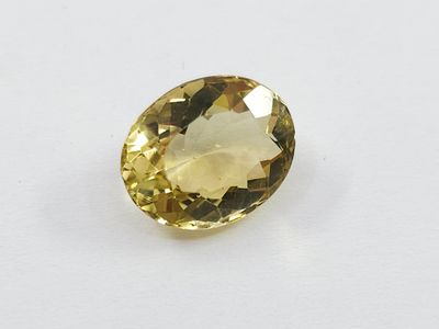 a yellow sapphire stone on a white surface