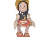 peluche représentant une petite fille assise sur une chaise, avec une étiquette portant son nom