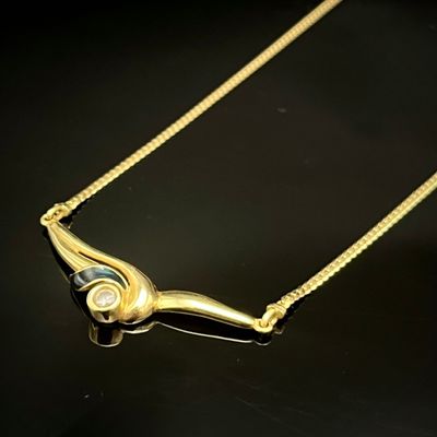un collier en or orné d'un diamant, posé sur un fond noir