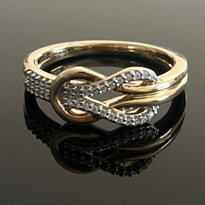 une image d'une bague en or et en diamant sur une surface noire