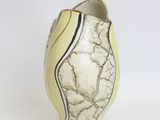 a white and black vase sitting on a white surface