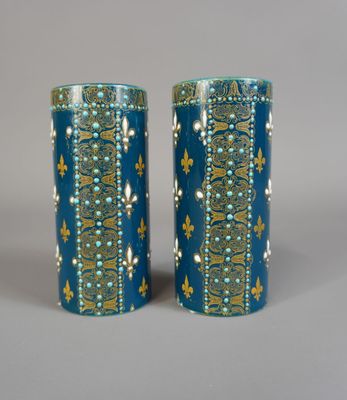 une paire de vases bleus ornés de motifs dorés sur un fond gris