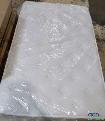 un matelas emballé dans du plastique, posé par terre