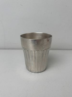 silver metal cup on a white table with a white background