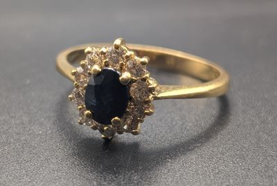 Gros plan sur une bague en or sertie d'une pierre bleue entourée de diamants blancs