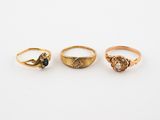 three gold rings, one with a black diamond and one with a white diamond, on a white background