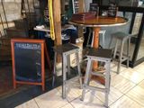 two stools sitting in front of a table with a chalk board on it