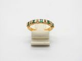 a close up of a gold ring with green stones on it