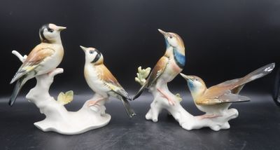 three figurines of birds sitting on a tree branch