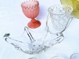 a glass bowl with a flower on top of it next to other glass dishes