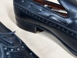 a pair of black shoes with holes on them sitting on a white surface