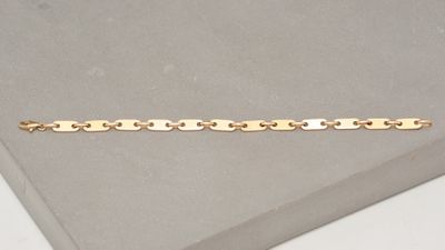 gros plan d'un bracelet en or sur une surface blanche