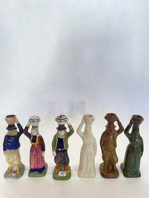 cinq figurines de couleurs et de tailles différentes sont alignées sur une surface blanche