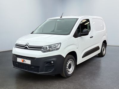 La camionnette blanche est garée dans une pièce au sol noir.