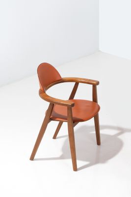 une chaise en bois avec une assise en cuir dans une pièce blanche