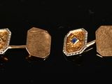 three pairs of gold and sapphire cufflinks on a black surface
