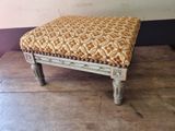 a small foot stool with a patterned seat on a wooden floor