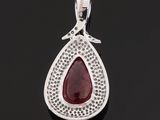 a silver pendant with a tear shaped red stone surrounded by small white diamonds