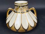 un vase doré et blanc posé sur une surface noire