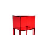 La petite table rouge a deux pieds et un plateau en verre.