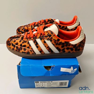baskets Adidas à imprimé léopard avec des lacets orange, posées sur une boîte bleue