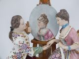 two figurines of women sitting in front of a mirror
