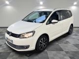une Volkswagen Touran blanche garée dans une pièce au sol à carreaux