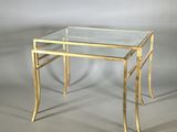 une photo d'une table basse en verre et en laiton sur fond gris