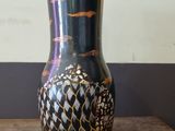 a black and gold vase sitting on a wooden table