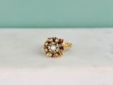 un gros plan d'une bague en or ornée d'une fleur, posée sur une table
