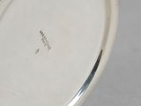 an antique silver plate with a silver handle on a gray surface