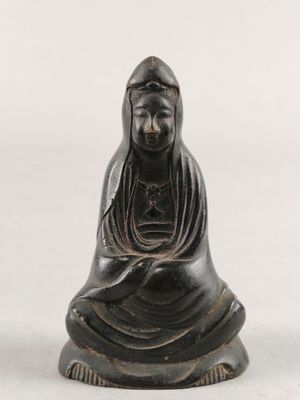 une statue noire représentant une femme assise sur une surface blanche
