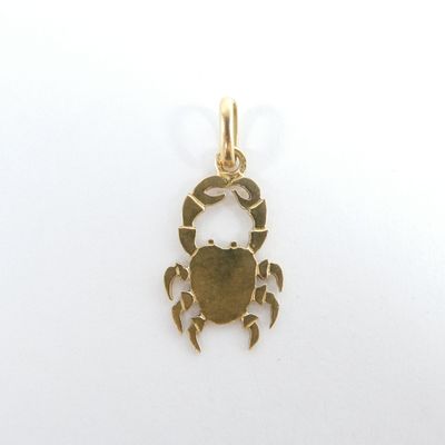 une petite breloque en forme de crabe doré sur fond blanc