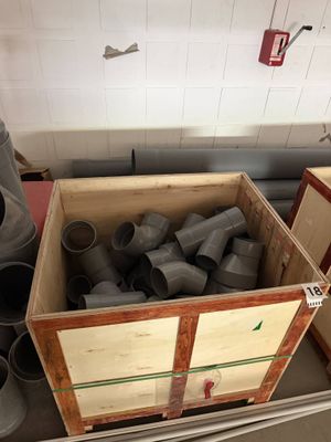une boîte remplie de raccords de tuyauterie posée par terre