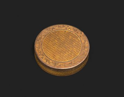 a small gold box with a floral design on the lid
