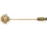 un gros plan d'une broche en or ornée de perles