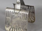 un objet en argent orné d'un oiseau, posé sur une table
