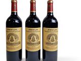 three bottles of red wine sitting next to each other on a white surface