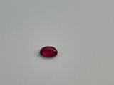 a single red stone sitting on top of a white surface
