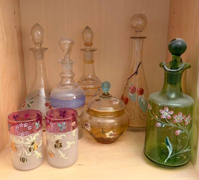 many different colored glass bottles and glasses on a shelf