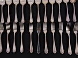a lot of forks and spoons on a black table