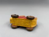 yellow and red wooden toy truck with wheels on a gray surface